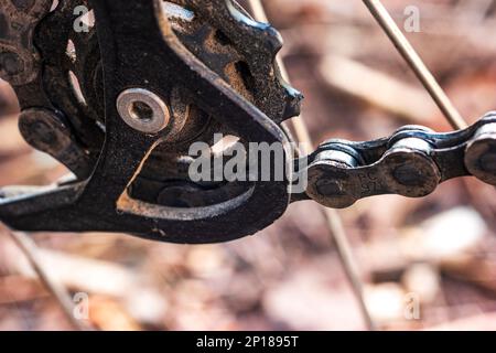 Macinato vecchio sporco montagna moto posteriore derailleur cog e catena maglia macro primo piano. Foto Stock