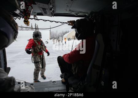 Alaska Army Guard SPC. Matthew Tucker, a sinistra, una medica di volo, e il personale Sgt. Brad McKenzie, un capo equipaggio e un operatore di sollevamento, entrambi assegnati a Golf Company, distaccamento 2, 2-211th Generale supporto Aviazione Battaglione, assistere Special Tactics Airmen, assegnato a 24th Special Operations Wing, distaccamento 1, con addestramento di evacuazione medica, A Camp Mad Bull su Joint base Elmendorf-Richardson, Alaska, 10 gennaio 2023. Gli equipaggi della Guardia militare hanno anche condotto operazioni di inserimento aereo e sollevamento con le squadre Special Tactics. Il battaglione di aviazione generale di supporto della Guardia Nazionale dell'Alaska si allena regolarmente Foto Stock