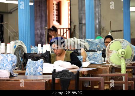 Donne cubane che lavorano su vecchie macchine da cucire. Seamstress cucita il tessuto in officina Foto Stock