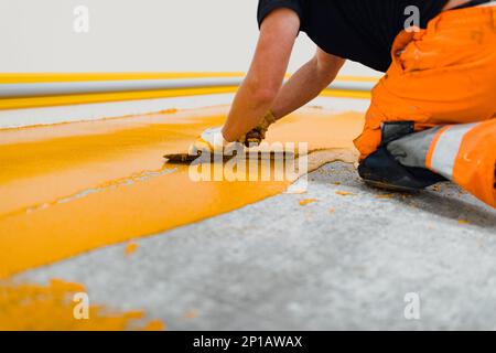 l'applicatore epossidico per pavimenti esegue lavori di verniciatura con malta epossidica poliuretanica Foto Stock