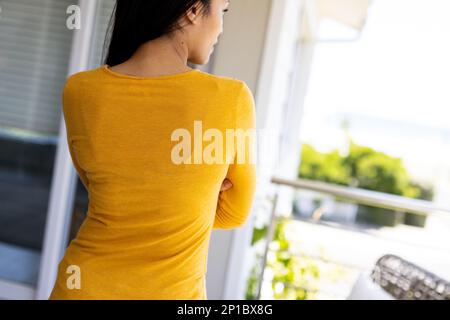 Donna biraciale che indossa una camicia gialla a maniche lunghe con spazio copia Foto Stock