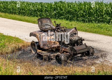 Trattore rasaerba danneggiato dal fuoco. Manutenzione attrezzature per prato, riparazione e concetto di assicurazione proprietari di casa. Foto Stock