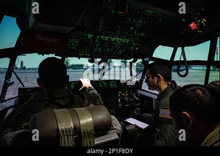 Due piloti del 37th Airlift Squadron hanno allestito i controlli per un simulatore di velivoli C-130J Super Hercules alla base aerea di Ramstein, Germania, 1 febbraio 2023. I piloti si allenano regolarmente sul simulatore dell'aeromobile invece di viaggiare in altre località per allenarsi, il che fa risparmiare a Ramstein circa $350.000 dollari l'anno. Foto Stock