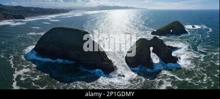 Il sole dell'Oceano Pacifico si bagna su scoscese e sceniche cataste marine al largo della costa settentrionale dell'Oregon, non lontano da Tillamook. Foto Stock