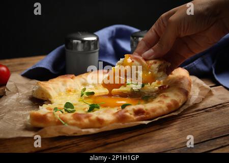 Donna che mangia delizioso Khachapuri Adjarian al tavolo di legno, primo piano Foto Stock
