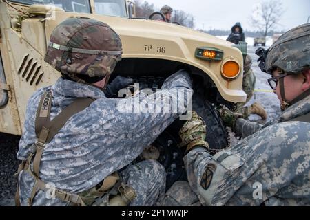 10th soldati di montagna lavorano insieme per mettere catene da neve su un HMMV in meno di 10 minuti. Le squadre gareggiano per il tempo più veloce prima di passare all'esercizio successivo. Foto Stock