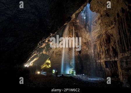 Vista della cascata del torrente che scorre lungo il diasmo nella camera della grotta con i visitatori, Fell Beck, Gaping Gill, Ingleborough, Yorkshire Dales N.P. Foto Stock