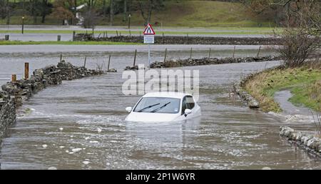 Auto abbandonata bloccata in acqua di alluvione sulla strada vicino Hawes, Wensleydale, Yorkshire Dales N.P., North Yorkshire, Inghilterra, Regno Unito Foto Stock