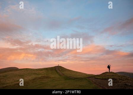 Il bellissimo paesaggio del tramonto invernale sopra Latrigg è caduto nel Lake District con due persone in cima alla collina che ammirano il tramonto Foto Stock