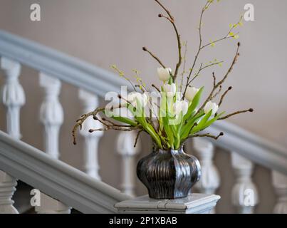 Semplice composizione floreale primaverile di tulipani bianchi e rami fioriti Foto Stock