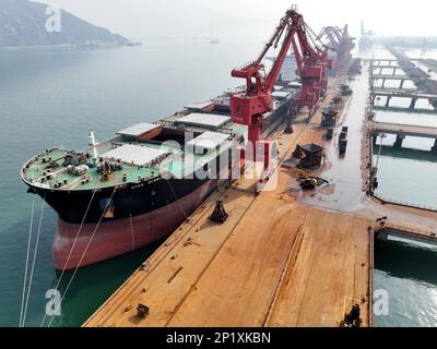 LIANYUNGANG, CINA - 4 MARZO 2023 - il minerale di ferro importato viene scaricato e accatastato nel porto di Lianyungang, nella provincia di Jiangsu della Cina orientale, il 4 marzo 202 Foto Stock