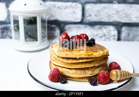Deliziosi pancake con fragola, mora e miele, primo piano. Foto Stock