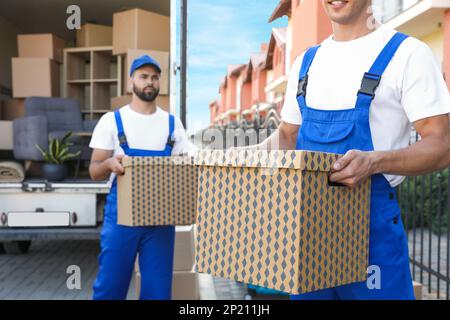 Lavoratori che scaricano scatole da furgoni all'aperto. Servizio in movimento Foto Stock