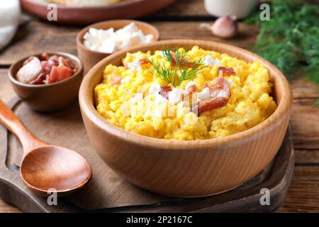 Gustoso banosh servito con brynza e cracklings di maiale su tavolo di legno, primo piano. Piatto tradizionale ucraino Foto Stock