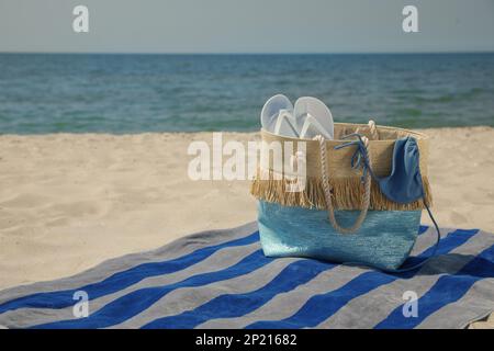 Telo da spiaggia con borsa, infradito e costume da bagno sulla sabbia Foto Stock