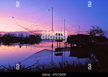 La rete da pesca si riflette sulla superficie dell'acqua calma al tramonto (Porto Corsini) Foto Stock