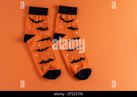 Calzini arancioni con pipistrelli. Costume di abbigliamento per la festa di Halloween. Vista dall'alto della calza vivace e multicolore. Spazio di copia. Foto Stock
