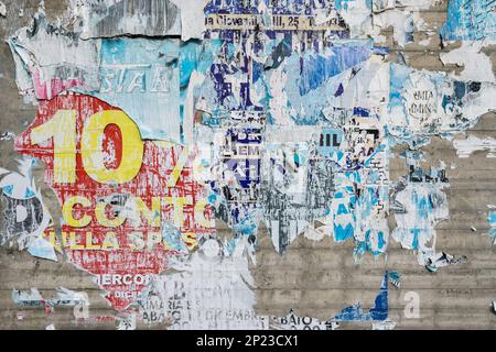 Poster colorati strappati su una vecchia parete grunge come sfondo astratto creativo. Foto Stock