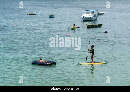 Salvador, Bahia, Brasile - 14 gennaio 2022: La gente si diverte a fare una passeggiata a nuoto stand-up sulla spiaggia di Porto da barra a Salvador, Bahia. Foto Stock