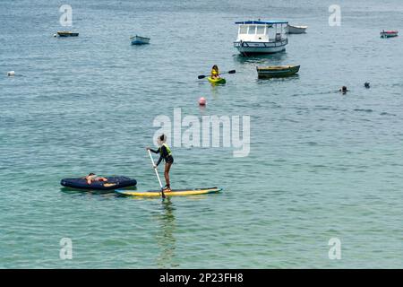 Salvador, Bahia, Brasile - 14 gennaio 2022: La gente si diverte a fare una passeggiata a nuoto stand-up sulla spiaggia di Porto da barra a Salvador, Bahia. Foto Stock