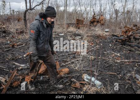 Gli uomini locali smantellano i resti di attrezzature militari russe distrutte e bruciate per rottami metallici, regione di Kharkiv, Ucraina. Guidando lungo le strade della regione di Kharkiv, più vicino si arriva a Donbas, le attrezzature militari più bruciate e rotte che si vede sul lato della strada, nei campi e nelle cinghie forestali. In uno di questi nastri forestali abbiamo visto una grande quantità di apparecchiature russe bruciate. Quando abbiamo smesso di scattare foto, abbiamo visto diversi uomini e adolescenti che si rimesero sistematicamente. Stavano smontandolo per i rottami di metallo, per i quali ricevono 2 crivnie per chilogrammo. Non possono raccogliere più t Foto Stock