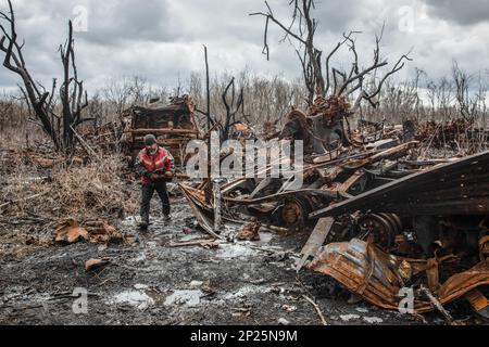 Gli uomini locali smantellano i resti di attrezzature militari russe distrutte e bruciate per rottami metallici, regione di Kharkiv, Ucraina. Guidando lungo le strade della regione di Kharkiv, più vicino si arriva a Donbas, le attrezzature militari più bruciate e rotte che si vede sul lato della strada, nei campi e nelle cinghie forestali. In uno di questi nastri forestali abbiamo visto una grande quantità di apparecchiature russe bruciate. Quando abbiamo smesso di scattare foto, abbiamo visto diversi uomini e adolescenti che si rimesero sistematicamente. Stavano smontandolo per i rottami di metallo, per i quali ricevono 2 crivnie per chilogrammo. Non possono raccogliere più t Foto Stock