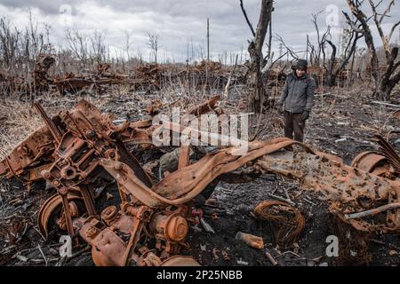 Gli uomini locali smantellano i resti di attrezzature militari russe distrutte e bruciate per rottami metallici, regione di Kharkiv, Ucraina. Guidando lungo le strade della regione di Kharkiv, più vicino si arriva a Donbas, le attrezzature militari più bruciate e rotte che si vede sul lato della strada, nei campi e nelle cinghie forestali. In uno di questi nastri forestali abbiamo visto una grande quantità di apparecchiature russe bruciate. Quando abbiamo smesso di scattare foto, abbiamo visto diversi uomini e adolescenti che si rimesero sistematicamente. Stavano smontandolo per i rottami di metallo, per i quali ricevono 2 crivnie per chilogrammo. Non possono raccogliere più t Foto Stock