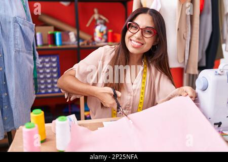 Giovane bella donna araba su misura sorridente sicuro di taglio panno presso atelier Foto Stock