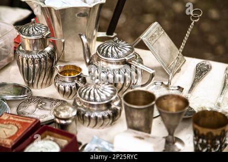 Argento antico teiere, creamer e altri utensili in un mercato delle pulci. Vecchi articoli metallici da tavola gli oggetti collezionabili in una vendita di garage Foto Stock