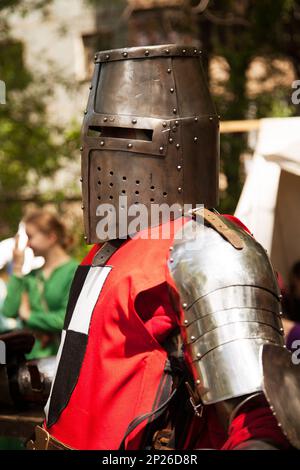 Medioevo costume al torneo di cavaliere. Storico medievale - rievocazione di un uomo che indossa metallo grande casco e red armor suit Foto Stock