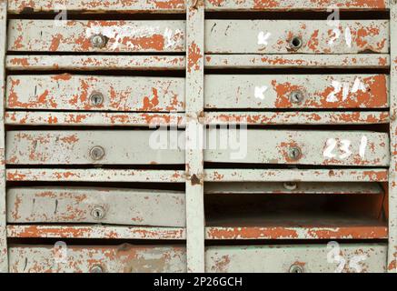 Blocco di molto vecchio danneggiato le cassette postali in un edificio di appartamenti. Molti vintage postboxes dipinta in una fila di sfondo vintage Foto Stock