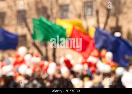 La folla di persone in un giorno di maggio marzo portando palloncini colorati e bandiere sfondo sfocato. Parade festival o concetto astratto sfondo sfocato Foto Stock