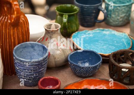 Un sacco di stoviglie a mano - coppe in ceramica, piastre in ceramica shop. Colorato di blu e arancione sfondo clayware Foto Stock