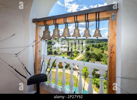 Campane ortodosse sul campanile della chiesa. Vista dall'alto del paese e del lago in una giornata estiva. Villaggio di Sopiny, regione di Novgorod, Russia Foto Stock