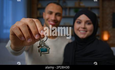 Proprietari felici proprietà multirazziale famiglia sposi coppia etnica mostrando mazzo di chiavi nuovo casa ricollocazione proprietari di case uomo afro-americano donna musulmana Foto Stock