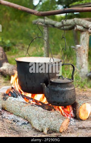 Due bollitori da turismo fumati sopra il fuoco del campo. Processo di cottura sulla natura. Foto Stock