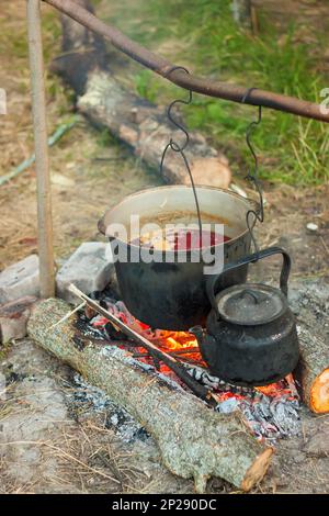 Due bollitori da turismo fumati sopra il fuoco del campo. Processo di cottura sulla natura. Foto Stock