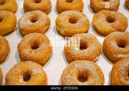 Ciambelle con zuccheri esposti in scaffale per la colazione, Foto Stock