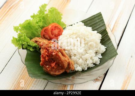 Ayam Geprek è popolare Street Food in Indonesia. Prodotto da pollo croccante schiacciato in salsa all'aglio al peperoncino di Bawang Sambal. Servito con riso e verdure Foto Stock