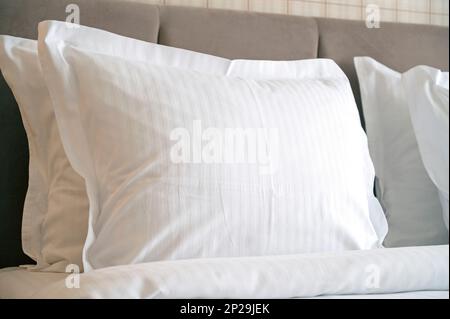 Primo piano dei cuscini bianchi su un letto dell'hotel, cuscino bianco pulito in una camera confortevole Foto Stock