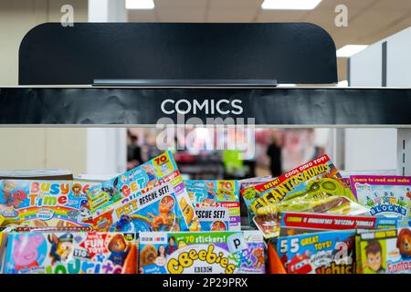 Fuoco poco profondo della bandiera del fumetto vista all'interno di un newsAgent popolare della strada. Una selezione di fumetti per bambini può essere vista impilata sullo scaffale. Foto Stock