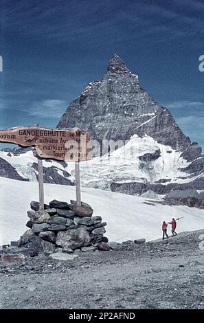 Stazione Trockener Steg con sciatori estivi e il cartello per il Gandegghütte. Zermatt, Visp, cantone del Vallese, Svizzera, 1975 Foto Stock