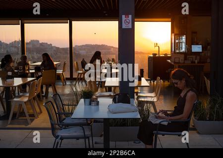 Ramallah, Ramallah e al-Bireh Governatorato, Palestina, 28 luglio 2022: Donna che guarda cellulare e persone cena a al-Matal Ristorante Terrazza Aga Foto Stock