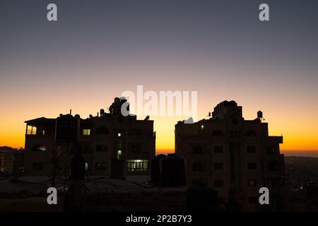 Arab Town Building Silhouette al crepuscolo con serbatoi d'acqua in cima e cielo colorato Foto Stock