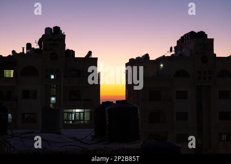 Arab Town Building Silhouette al crepuscolo con serbatoi d'acqua in cima e cielo colorato Foto Stock