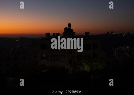 Arab Town Building Silhouette al crepuscolo con serbatoi d'acqua in cima e cielo colorato Foto Stock