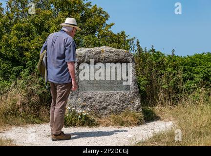 Uomo anziano che indossa un cartello di lettura con cappello di Panama su Golden Cap sulla costa di Jurassic, Dorset, Inghilterra, Regno Unito Foto Stock