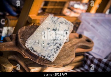 Un pezzo di formaggio francese con muffa blu su un pannello di legno in vendita Foto Stock