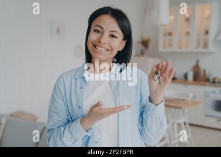 Sorridente tenant femminile o proprietario di abitazione che mostra le chiavi alla nuova sede. Donna felice noleggiatore che tiene la chiave per l'appartamento, guardando la fotocamera. Vendita immobiliare. Noleggio Foto Stock