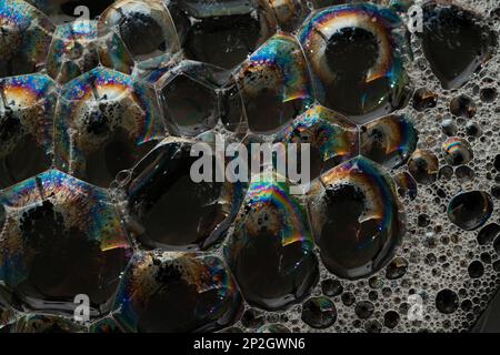 Primo piano, macrofone di una bolla di sapone, arcobaleno multicolore con colori giallo, viola, rosa, blu e verde su sfondo nero. Foto Stock